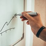 Une main dessine un graphique sur un tableau blanc